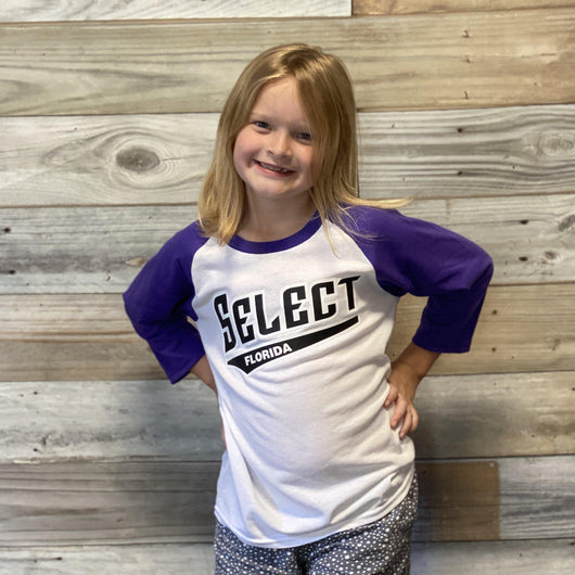 Girl wearing raglan tee with purple sleeves and white body. Text across chest says Florida Select.